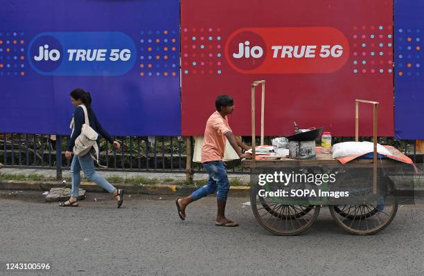 Vendor pushing a hand cart walks past Jio 5G branding in Mumbai. Reliance Jio 5G network service is set to roll out in the month of October 2022....