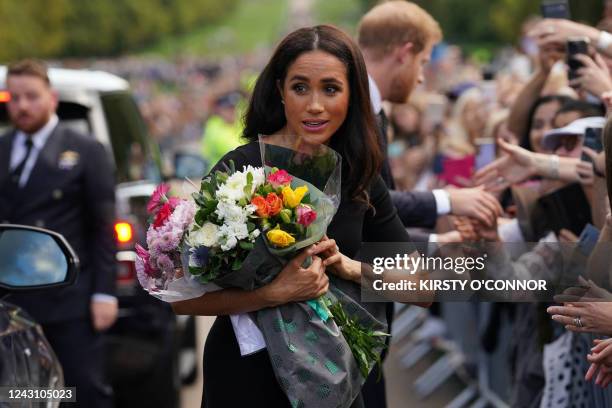 Meghan, Duchess of Sussex collects flowers as she chats with well-wishers on the Long walk at Windsor Castle on September 10 two days after the death...