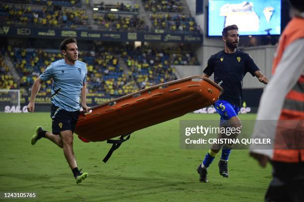 Players and emergency service members run holding a stretcher during a play interruption as a supporter fainted in the tribunes during the Spanish...