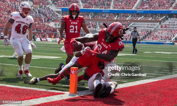 Chris Curry of the Utah Utes scores a touchdown against Rodrick Ward and Jason Thomas of the Southern Utah Thunderbirds during the first half of...