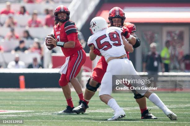 Cameron Rising of the Utah Utes drops back to pass under pressure from Cameron Dahle of the Southern Utah Thunderbirds during the first half of their...