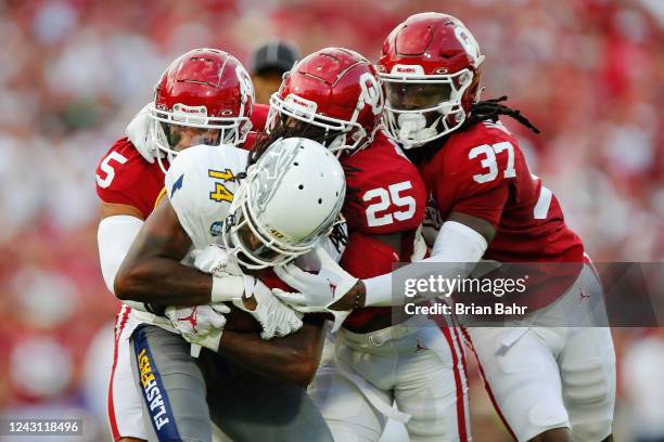 Defensive backs Billy Bowman Jr. #5, Justin Broiles, and Justin Harrington of the Oklahoma Sooners gang up on wide receiver Dante Cephas of the Kent...