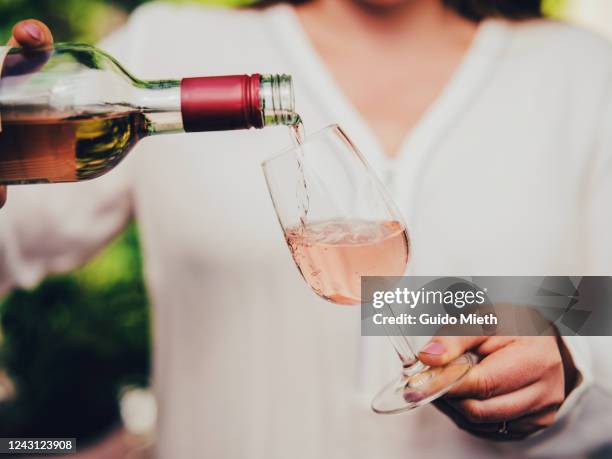 woman pouring wine in glass. - vino rosado fotografías e imágenes de stock
