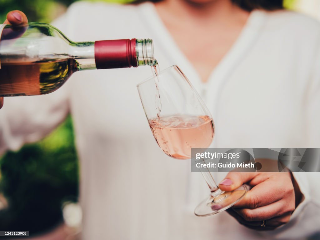 Woman pouring wine in glass.