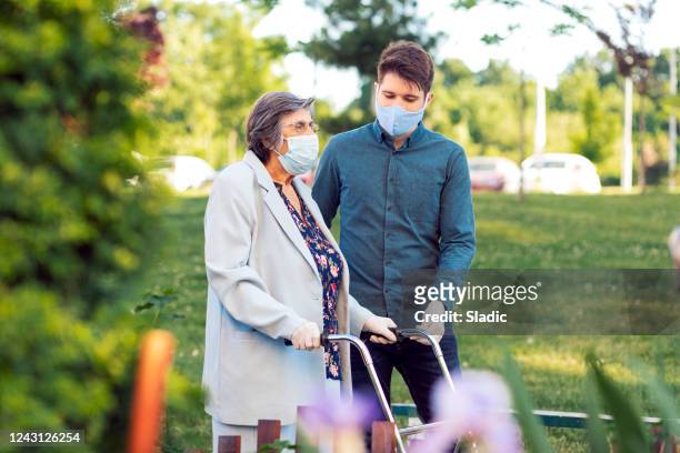 young man helping senior woman walking in the street - assistance stock pictures, royalty-free photos & images