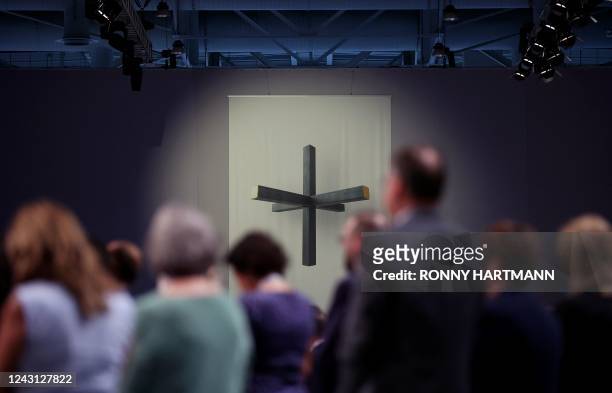 Delegates standing in front of a 3D cross projected on the wall during the CDU party congress in Hanover, northern Germany on September 9, 2022.
