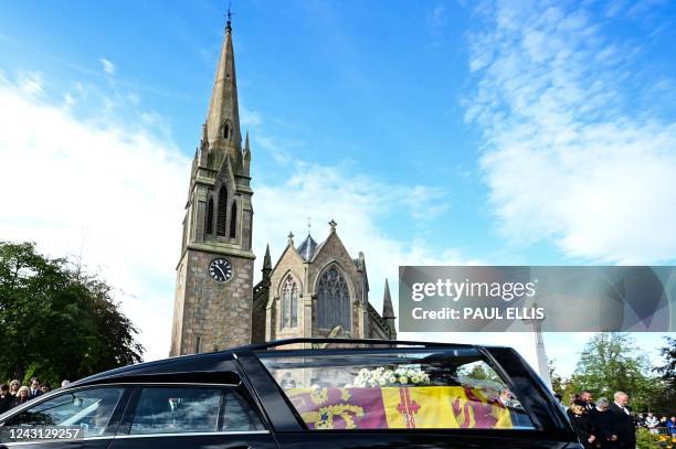 Members of the Public pay their respects as they hearse carrying the coffin of Queen Elizabeth II, draped in the Royal Standard of Scotland, is...