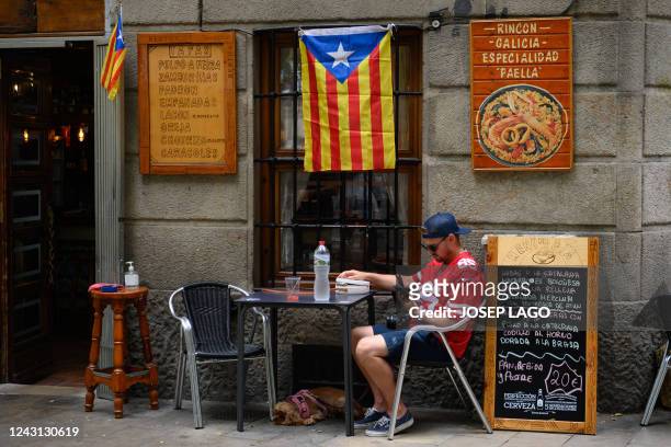 Man looks at his mobile phone on a bar terrace under a Catalan pro-independence "Estelada" flag during a protest marking the "Diada", the national...