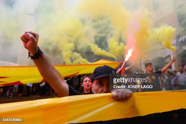Demonstrators wave Catalan pro-independence "Estelada" flag and light flares as they sing a Catalan anthem during a protest marking the "Diada", the...