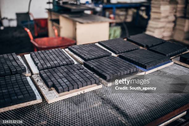 nahaufnahme von kohlewürfeln für shisha in regalen in der fabrik - briketts stock-fotos und bilder