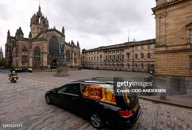 The hearse carrying the coffin of Queen Elizabeth II, draped in the Royal Standard of Scotland, is driven past St Giles' Cathedral in Edinburgh...