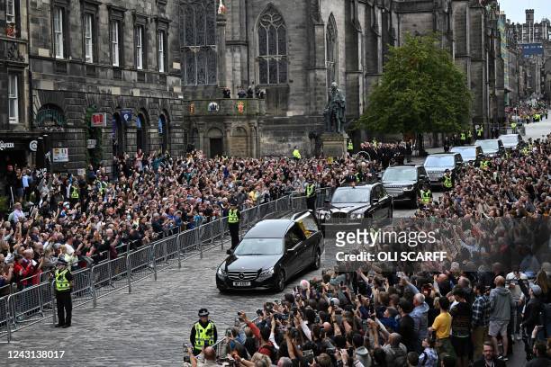 Members of the public watch the hearse carrying the coffin of Queen Elizabeth II, as it is driven through Edinburgh towards the Palace of...