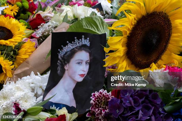 Close up of floral tributes and images of the Queen as public gather to lay flowers at a temporary memorial garden in Green Park following the death...