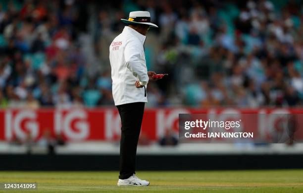 India's umpire Nitin Menon checks his light meter during play on the fourth day of the third Test cricket match between England and South Africa at...