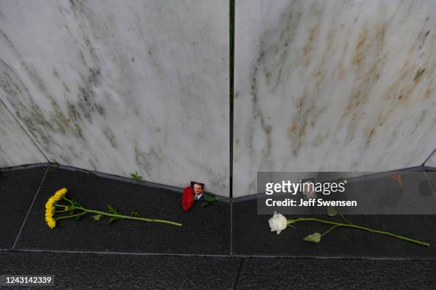 Photos of Thomas Burnett and William Joseph Cashman with flowers at their stones at the Wall of Names during a ceremony commemorating the 21st...