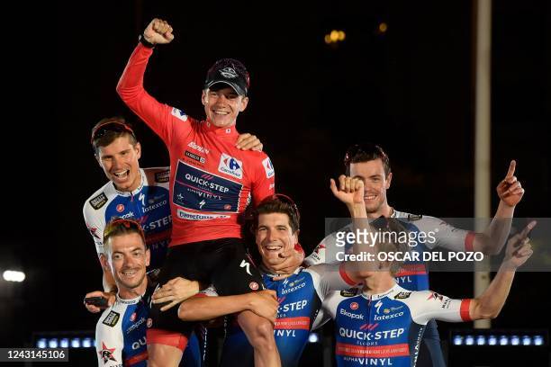 Team Quick Step's Belgian rider Remco Evenepoel celebrates with teammates on the podium wearing the overall leader's red jersey after the 21st and...