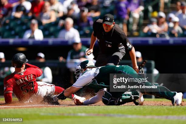 Christian Walker of the Arizona Diamondbacks slides in safely ahead of the tag by Brian Serven of the Colorado Rockies as home plate umpire Chad...