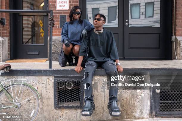 Drusilla Arhin is seen wearing a shirt Yeezy Gap Balenciaga, boots by Ego, gloves and glasses by Amazon Fashion and Joseph Holland is seen wearing a...