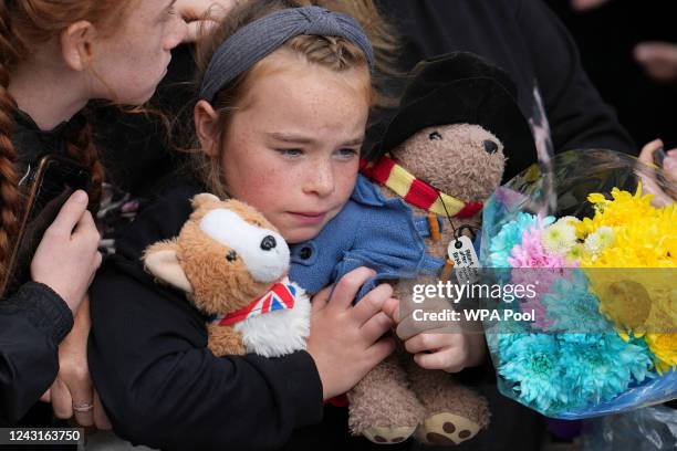 Young girl holds a Paddington bear and a Corgi dog stuffed toys while waiting to watch the Procession of Queen Elizabeth's coffin from the Palace of...