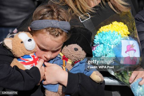 Young girl holds a Paddington bear and a Corgi dog stuffed toys while waiting to watch the Procession of Queen Elizabeth's coffin from the Palace of...