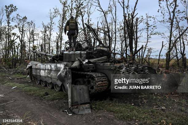 This photograph taken on September 11 shows a Ukranian soldier standing atop an abandoned Russian tank near a village on the outskirts of Izyum,...