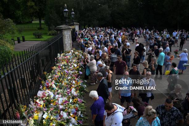People visit floral tributes outside the gates of Windsor Castle, west of London, on September 12 following the death of Queen Elizabeth II on...