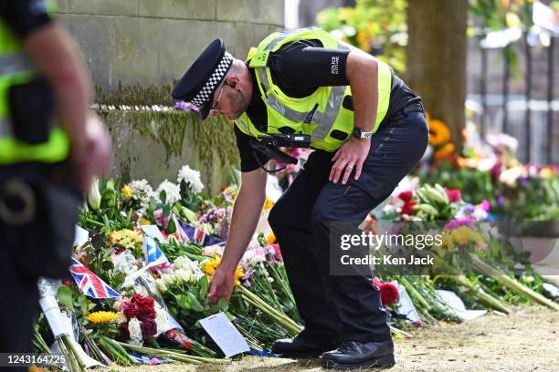 Police officer places flowers on behalf of a member of the public in the garden area outside the Palace of Holyroodhouse as the coffin of Queen...