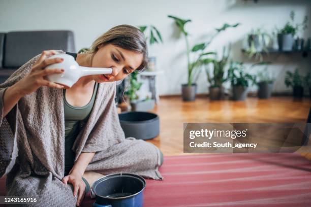 jonge vrouw die neti pot thuis gebruikt - human nose stockfoto's en -beelden