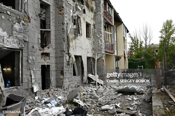Local residents stand outside their building partially destroyed by a missile strike on Kharkiv on September 12, 2022 amid the Russian invasion of...
