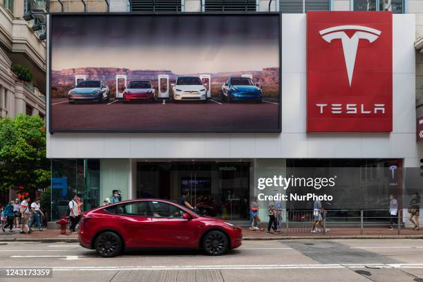 Hong Kong, China, 13 Sept 2022, A red Tesla car passes in front of a Tesla dealership in Wanchai.