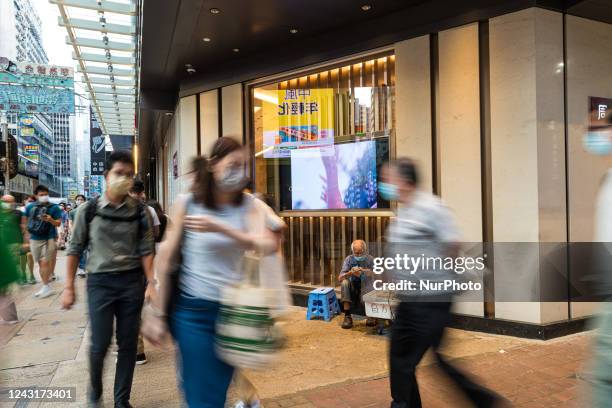 Hong Kong, China, 3 Sept 2022, An elderly man sells trinkets on Nathan road in Mongkok, as people breeze by..