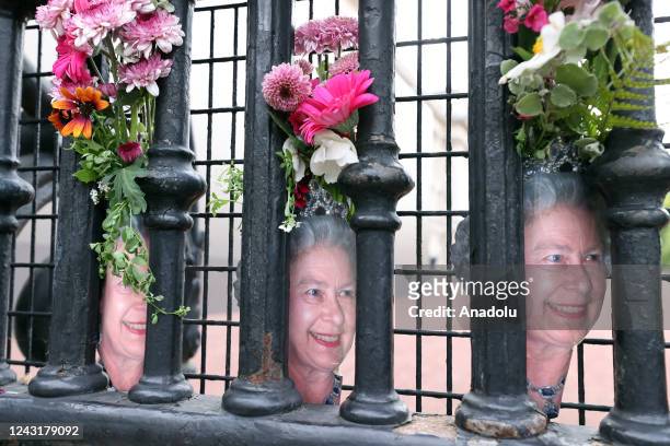 People gather to lay flowers and notes at Buckingham Palace and around for Queen Elizabeth II, who died at the age of 96, before her funeral ceremony...