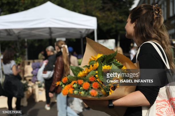 Woman buys flowers on a stall at Columbia Road Flower Market, in east London on September 11, 2022. Flower sales are set to blossom for the state...