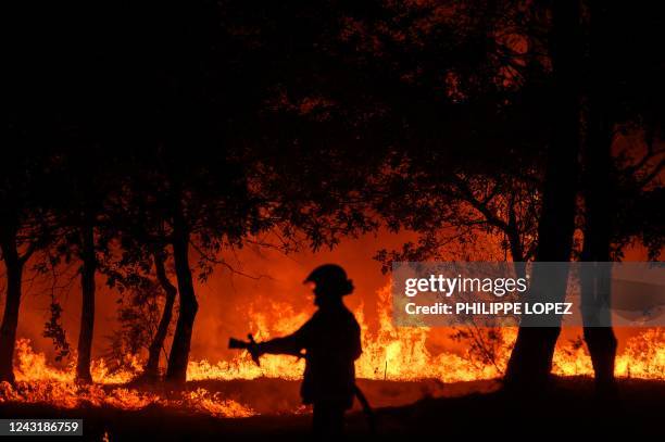 In this photograph taken on late September 12, 2022 a firefighter stands in front of flames at a night wildfire in Saumos near Bordeaux, southwestern...