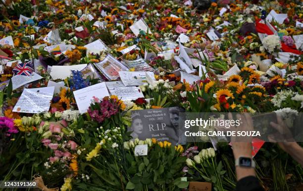 Members of the public look at flowers and tributes left in Green Park in London on September 13 following the death of Queen Elizabeth II on...