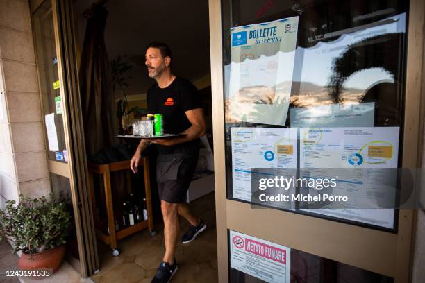 Lorenzo Pinamonte, owner of Hotel Nettuno, walks past electricity bills he has displayed in protest of the near 600 percent price hike of the August...