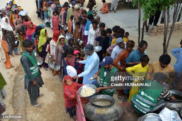 Displaced flood-affected people stand in a queue to receive food being distributed by Saylani Welfare Trust at a makeshift camp in flood-hit Sehwan...