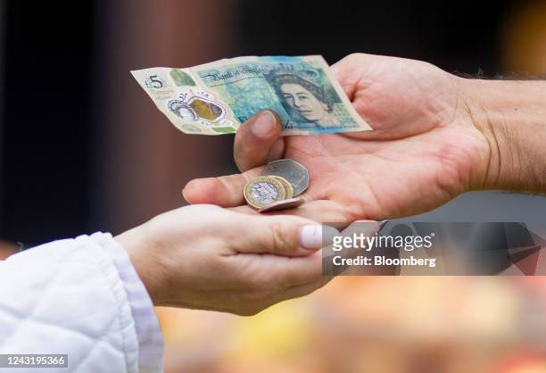 Stallholder gives change to a customer on a market stall selling produce in Barking, UK, on Tuesday, Sept. 13, 2022. As the UK enters a period of...