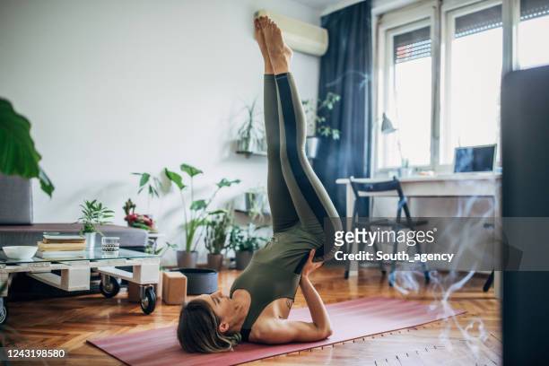 woman lying on upper back and holding her lower back in balance - active lifestyle stock pictures, royalty-free photos & images
