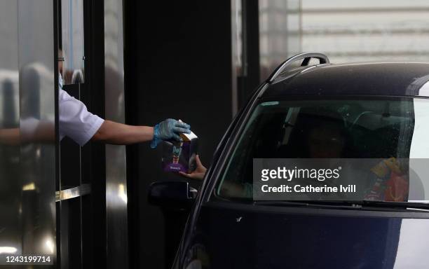 Member of the public receives his McDonald's Happy Meal order as the drive thru resumes trading on June 03, 2020 in Aylesbury, United Kingdom. The...