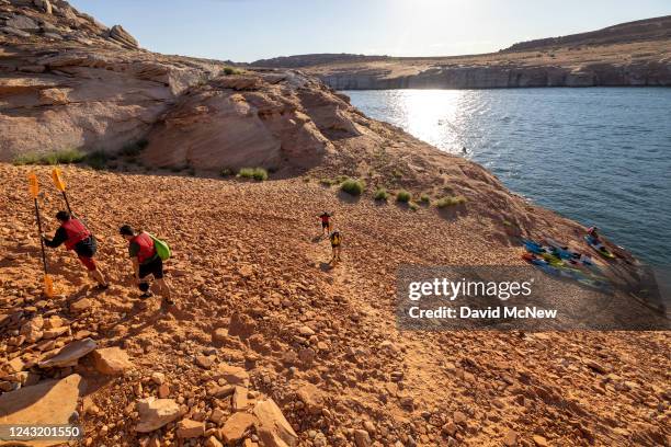 Kayakers ascend a steep and growing embankment between the unusable Antelope Point boat ramp and the water as the level of Lake Powell continues to...