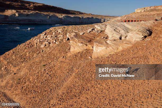 Man ascends a steep and growing embankment between the unusable Antelope Point boat ramp and the water as the level of Lake Powell continues to drop...