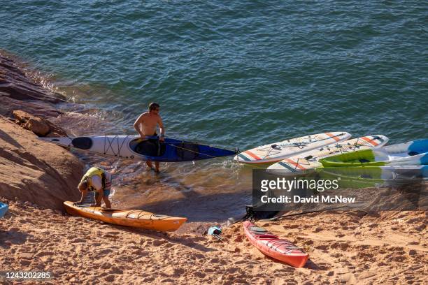 Kayakers tend to their boats as they arrive to the bottom of a steep and growing embankment between the unusable Antelope Point boat ramp and the...