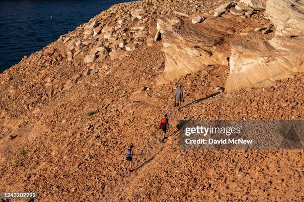 People ascend a steep and growing embankment between the unusable Antelope Point boat ramp and the water as the level of Lake Powell continues to...