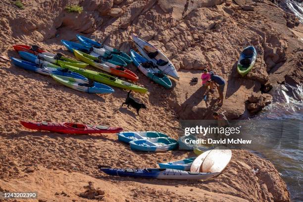 Kayakers tend to their boats as they arrive to the bottom of a steep and growing embankment between the unusable Antelope Point boat ramp and the...