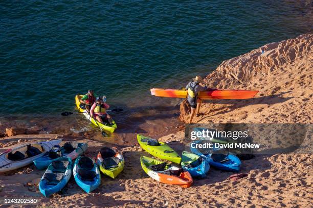 Kayakers arrive to the bottom of a steep and growing embankment between the unusable Antelope Point boat ramp and the water as the level of Lake...