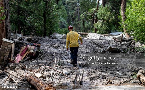 San Bernardino County firefighter walks precariously on wooden planks placed on top of a large mudslide which is blocking Prospect Drive on September...