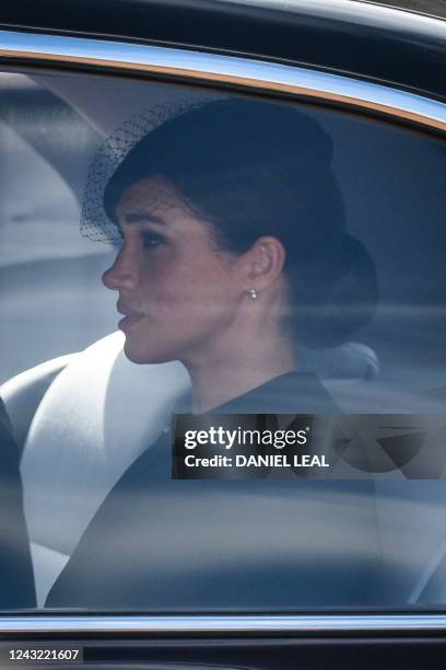Meghan, Duchess of Sussex is driven behind the coffin of Queen Elizabeth II, adorned with a Royal Standard and the Imperial State Crown and pulled by...