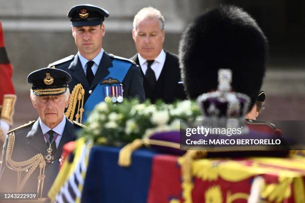 Britain's King Charles III and Britain's Catherine, Princess of Wales walk behind the coffin of Queen Elizabeth II, adorned with a Royal Standard and...