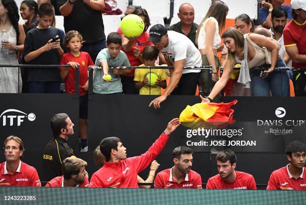 Spain's tennis player Carlos Alcaraz , next to Spain's tennis players Marcel Granollers and Pedro Martinez , receives a Spanish flag from a supporter...